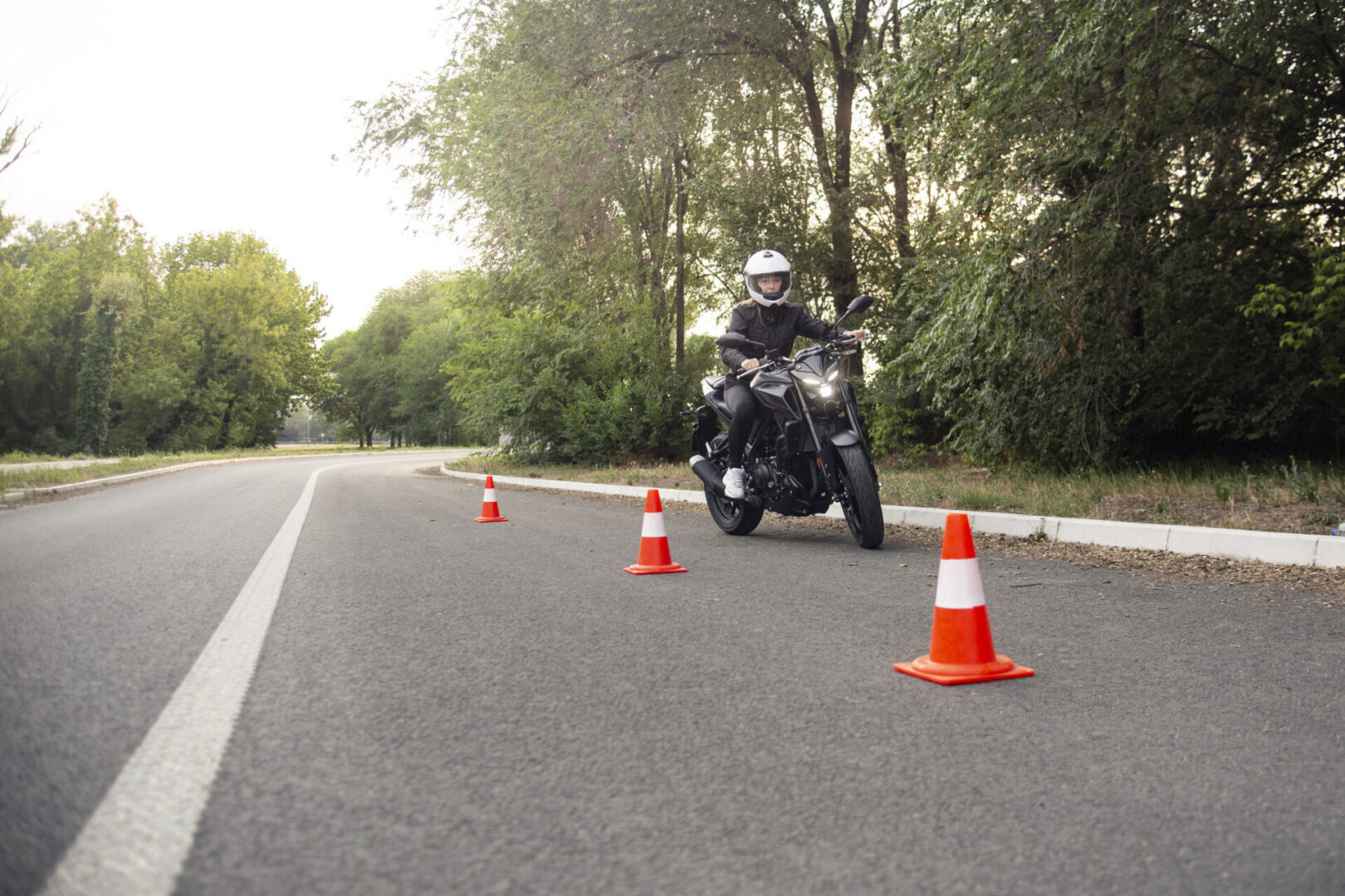 Young woman learning to ride a motorcycle on an obstacle course. About 25 years old, Caucasian female.