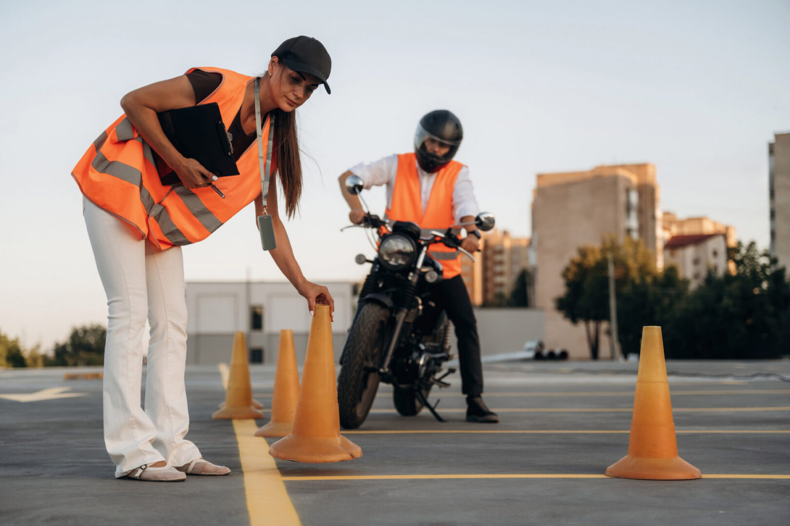 Placing the cones. Motorcycle driving license exam. Man and woman are in uniforms.